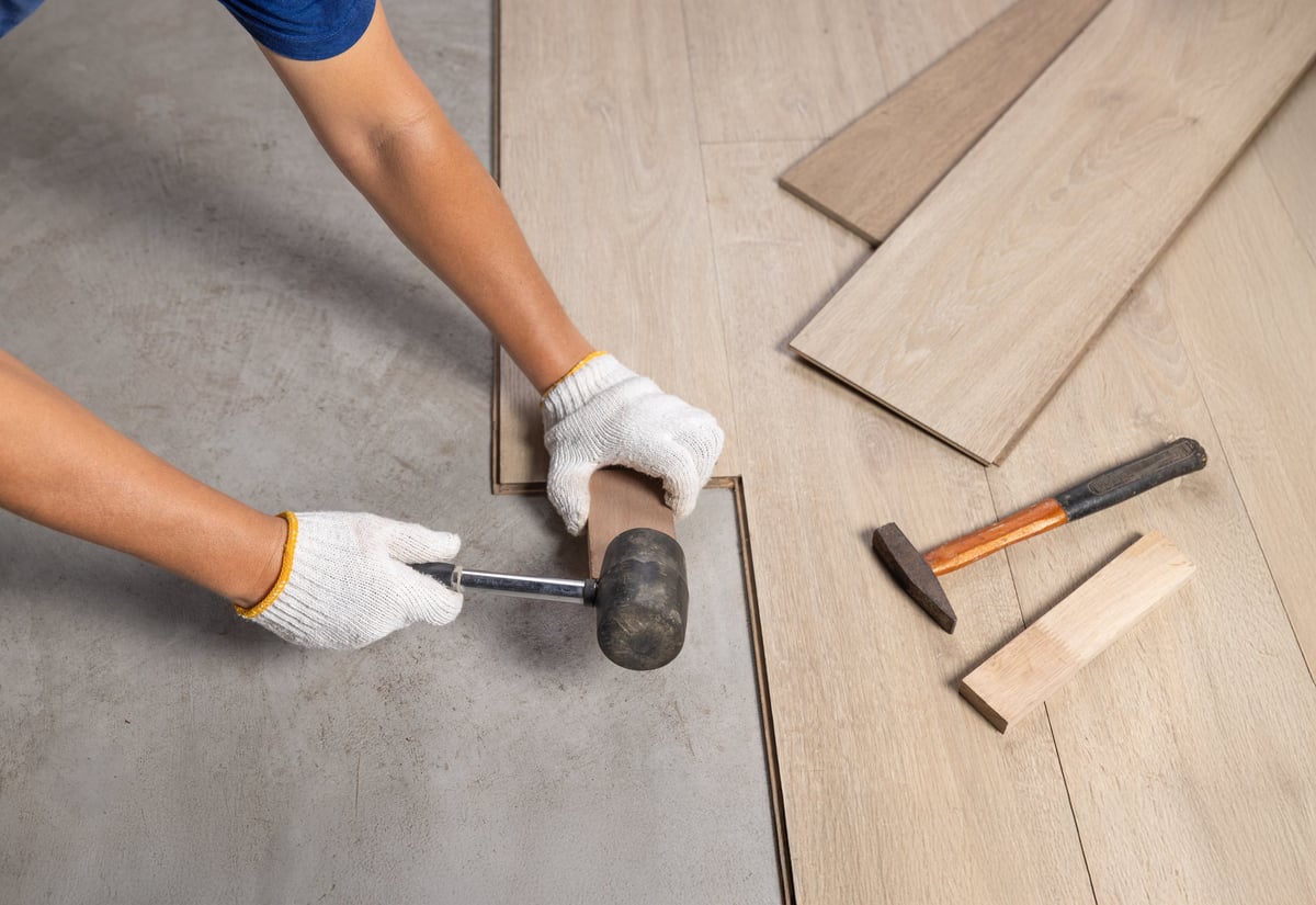 Handwerker verlegt Laminatboden bei einer Renovierung im Haus